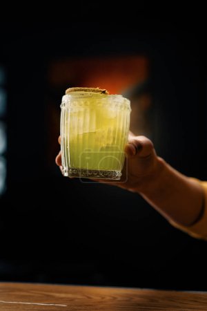 Foto de Cliente sosteniendo delicioso cóctel recién hecho Apple Smash con kiwi en el concepto de alcohol de fiesta de barra de mano - Imagen libre de derechos