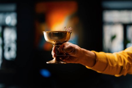 Photo for Close-up of a bar guest holding  ready-made delicious stewed fruit alcoholic cocktail in his hand - Royalty Free Image