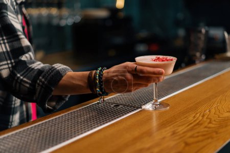 Foto de Un primer plano de un invitado de bar sosteniendo preparado sabroso cóctel alcohólico club de arándanos en su mano - Imagen libre de derechos