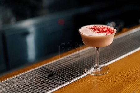 Téléchargez les photos : Délicieux cocktail club de bleuets rose fraîchement préparé avec des framboises se tient sur le bar en attendant les invités - en image libre de droit