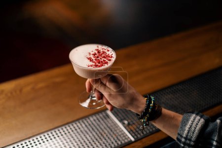 Téléchargez les photos : Gros plan d'un invité du bar tenant à la main un délicieux cocktail alcoolisé au club de myrtilles - en image libre de droit