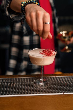 Téléchargez les photos : Le barman prépare un cocktail punch au lait et met des framboises hachées sur la boisson - en image libre de droit
