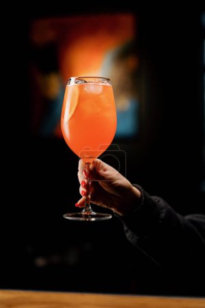 Photo for A client of a restaurant bar is holding delicious Aperol spritz cocktail in his hand close-up - Royalty Free Image