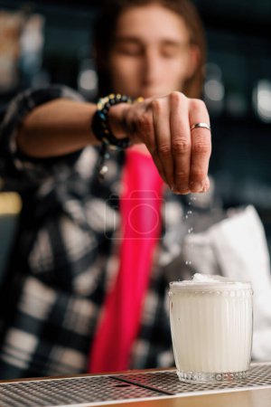 Téléchargez les photos : Jeune barman avec dreadlocks ajoute des copeaux de noix de coco coco cocktail paradis au bar - en image libre de droit