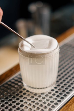 Téléchargez les photos : Le barman verse un délicieux cocktail prêt à l'emploi dans un verre transparent avec une passoire à alcool - en image libre de droit