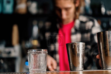 Foto de Herramienta del camarero para hacer cócteles una coctelera y un vaso en el mostrador de bar antes de comenzar a trabajar - Imagen libre de derechos