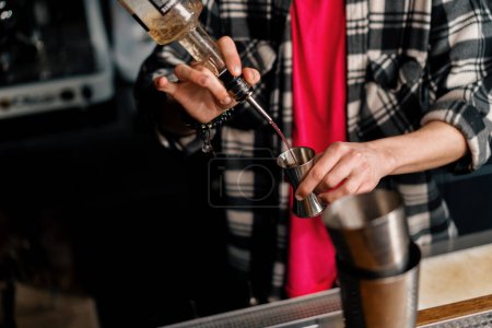 Foto de Un camarero profesional vierte alcohol en una taza de medir El proceso de hacer cócteles en un club en el primer plano del bar - Imagen libre de derechos