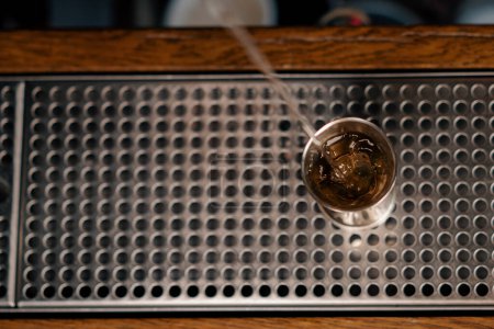 Téléchargez les photos : Un barman professionnel verse de l'alcool dans une tasse à mesurer Le processus de fabrication de cocktails dans un club dans un bar close-up - en image libre de droit