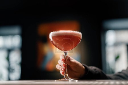 Photo for Customer holding delicious pink freshly made raspberry milk punch cocktail in hand bar drinks concept - Royalty Free Image