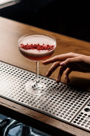 Photo for The customer takes a delicious pink freshly prepared raspberry milk punch cocktail from bar - Royalty Free Image