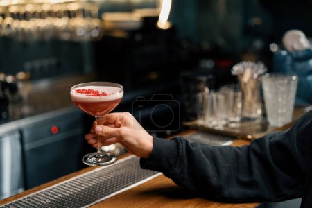 Photo for The customer takes a delicious pink freshly prepared raspberry milk punch cocktail from bar - Royalty Free Image