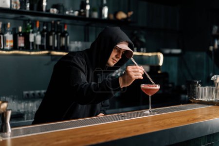 Téléchargez les photos : Le barman prépare un cocktail punch au lait et met des framboises hachées sur le dessus de la boisson avec des pinces - en image libre de droit
