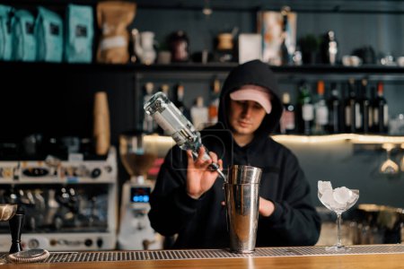 Foto de Un camarero profesional vierte alcohol en una taza de medir El proceso de hacer cócteles en un club en el bar - Imagen libre de derechos