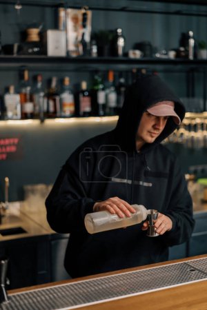 Téléchargez les photos : Un barman professionnel verse de l'alcool dans une tasse à mesurer Le processus de fabrication de cocktails dans un club dans un bar - en image libre de droit