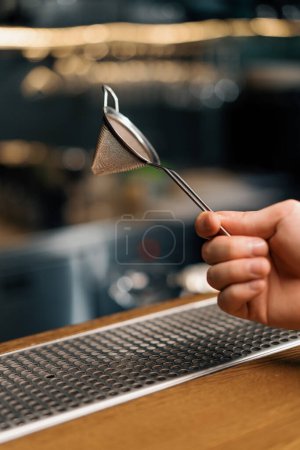 Téléchargez les photos : Outil de barman pour faire des cocktails barman tient passoire dans sa main sur le bar gros plan - en image libre de droit