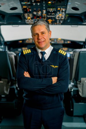Téléchargez les photos : Portrait du commandant de bord souriant en uniforme se préparant au poste de pilotage d'un simulateur d'aéronef de vol - en image libre de droit