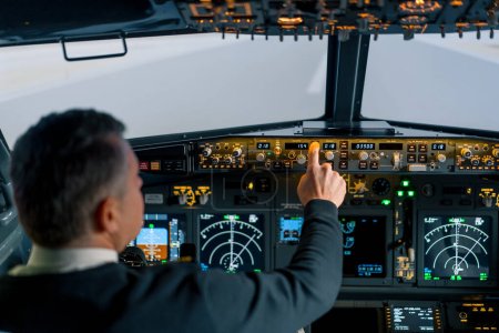 Téléchargez les photos : Le pilote appuie sur les boutons d'alimentation du tableau de commande pour commander l'aéronef devant le pare-brise du poste de pilotage - en image libre de droit