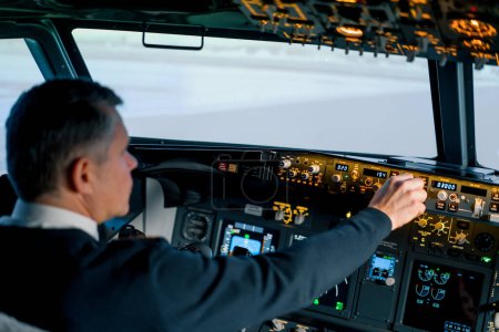 Téléchargez les photos : Le pilote appuie sur les boutons d'alimentation du tableau de commande pour commander l'aéronef devant le pare-brise du poste de pilotage - en image libre de droit