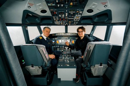 Téléchargez les photos : Pilote de poste de pilotage d'avion et jeune garçon étudiant souriant après l'entraînement simulateur de vol concept de divertissement - en image libre de droit