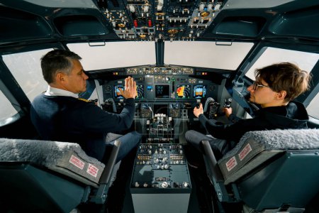 Foto de Un piloto experimentado instruye a un joven estudiante antes de un vuelo de entrenamiento en la cabina del simulador aéreo - Imagen libre de derechos