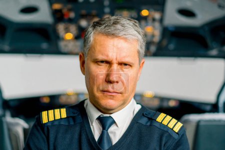 Photo for Portrait of serious airplane captain in uniform preparing flight in aero simulator cockpit - Royalty Free Image