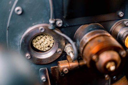 Foto de Los granos de café se rotan en una máquina para asar granos de café de cerca la producción de café artesanal - Imagen libre de derechos