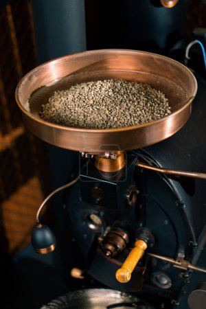 Foto de Los granos de café frescos se encuentran en la cámara de la máquina de café antes de asar para el café fragante de producción - Imagen libre de derechos
