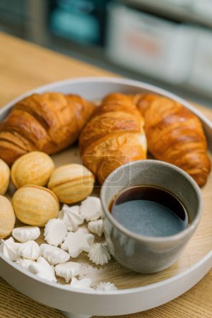 Photo for Delicious fresh meringue croissants and nuts with condensed milk and coffee on a table in cafe - Royalty Free Image