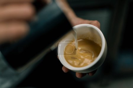 Téléchargez les photos : Barista faire latte art dans un café Mains masculines verser de la vapeur de lait dans une tasse de cappuccino avec motif - en image libre de droit