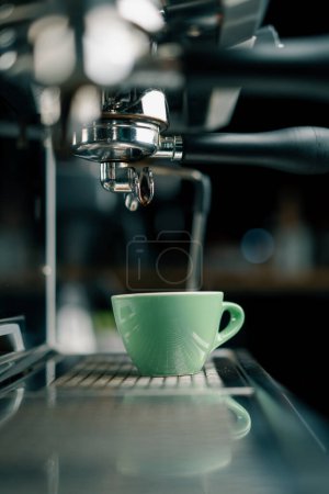 Foto de Verter el café fluye de la máquina en la taza haciendo bebida caliente usando el sostenedor del filtro flujos de café recién molidos - Imagen libre de derechos