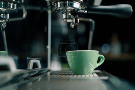 Verter el café fluye de la máquina en la taza haciendo bebida caliente usando el sostenedor del filtro flujos de café recién molidos