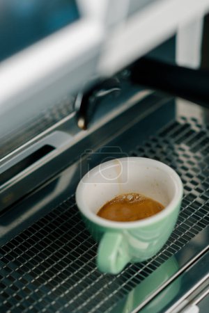 Foto de Verter el café fluye de la máquina en la taza haciendo bebida caliente usando el sostenedor del filtro flujos de café recién molidos - Imagen libre de derechos