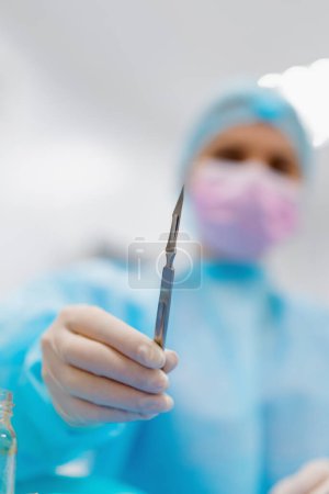 Foto de Enfermera o cirujano en guante estéril que sostiene el instrumento quirúrgico del cuero cabelludo en la mano durante la cirugía de cerca - Imagen libre de derechos