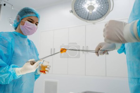Photo for Nurse in sterile glove hands surgical instruments tweezers wet gauze surgeon during operation - Royalty Free Image