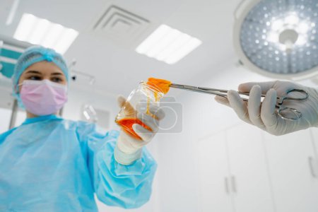 Foto de Enfermera en guantes estériles manos instrumentos quirúrgicos pinzas cirujano de gasa húmeda durante la operación - Imagen libre de derechos