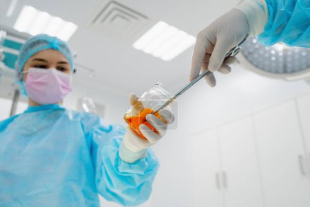 Téléchargez les photos : Infirmière en gants stériles mains instruments chirurgicaux pince à épiler gaze humide chirurgien pendant l'opération - en image libre de droit