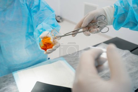 Photo for Nurse in sterile glove hands surgical instruments tweezers wet gauze surgeon during operation - Royalty Free Image