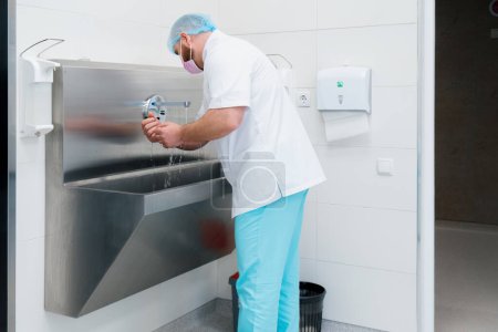 Photo for Disinfection procedure in the clinic the surgeon washes his hands in sink before the operation - Royalty Free Image