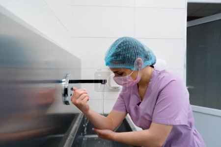 Téléchargez les photos : Procédure de désinfection à la clinique le chirurgien se lave les mains dans l'évier avant l'opération - en image libre de droit