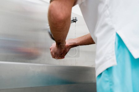 Photo for Disinfection procedure in the clinic the surgeon washes his hands in sink before the operation - Royalty Free Image