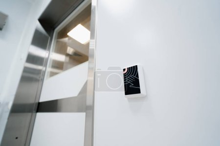 Téléchargez les photos : Bouton d'entrée sans contact machine d'ouverture de porte électronique à la main dans la salle d'opération clinique - en image libre de droit
