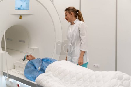 Photo for A professional radiologist in a medical clinic monitors a patient undergoing magnetic resonance imaging procedure - Royalty Free Image