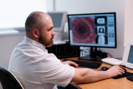 Photo for The patient undergoes computed tomography in the clinic the radiologist monitors the procedure and the results of scan - Royalty Free Image