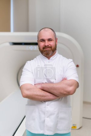 Téléchargez les photos : Sourire barbu médecin ct radiologue dans le bureau de tomodensitométrie attendre les patients avant de commencer le travail - en image libre de droit