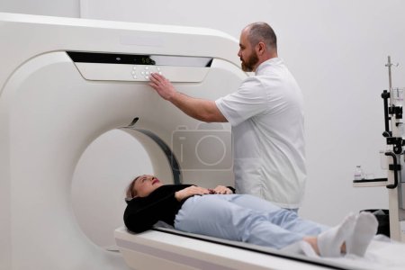 Foto de Un radiólogo realiza un procedimiento de tomografía computarizada en una clínica médica Se realiza un examen de cabeza al paciente - Imagen libre de derechos