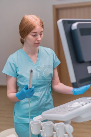 Téléchargez les photos : Un gynécologue tient un appareil d'échographie transvaginale dans ses mains pour diagnostiquer le patient à la clinique - en image libre de droit