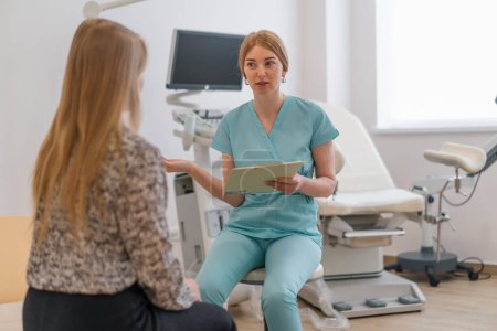 Foto de Un ginecólogo habla con un paciente durante una consulta médica en una clínica moderna en el consultorio ginecológico - Imagen libre de derechos