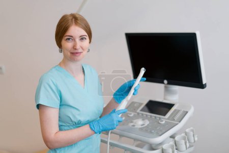 Téléchargez les photos : Un gynécologue tient un appareil d'échographie transvaginale dans ses mains pour diagnostiquer le patient à la clinique - en image libre de droit