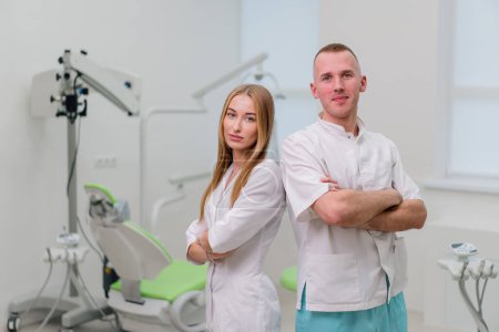 Photo for Portrait of beautiful young smiling colleagues of dentists standing in the dental office before the start of procedure - Royalty Free Image