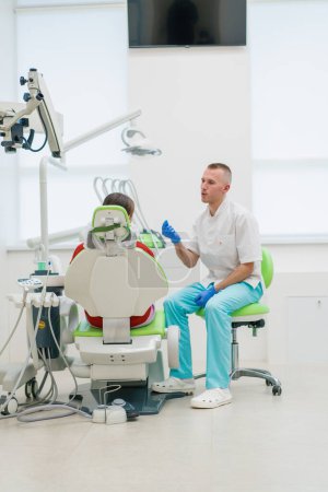 Téléchargez les photos : La patiente au rendez-vous chez le dentiste se plaint de maux de dents et de caries que le médecin lui conseille avant l'examen - en image libre de droit